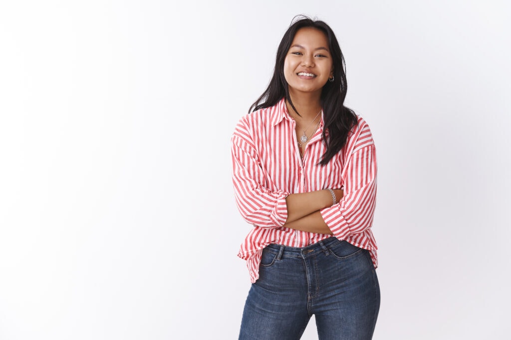 beauty, body positive and emotions concept. enthusiastic cute vietnamese woman in trendy office blouse cross hands over chest smiling and laughing talking with friends over white background
